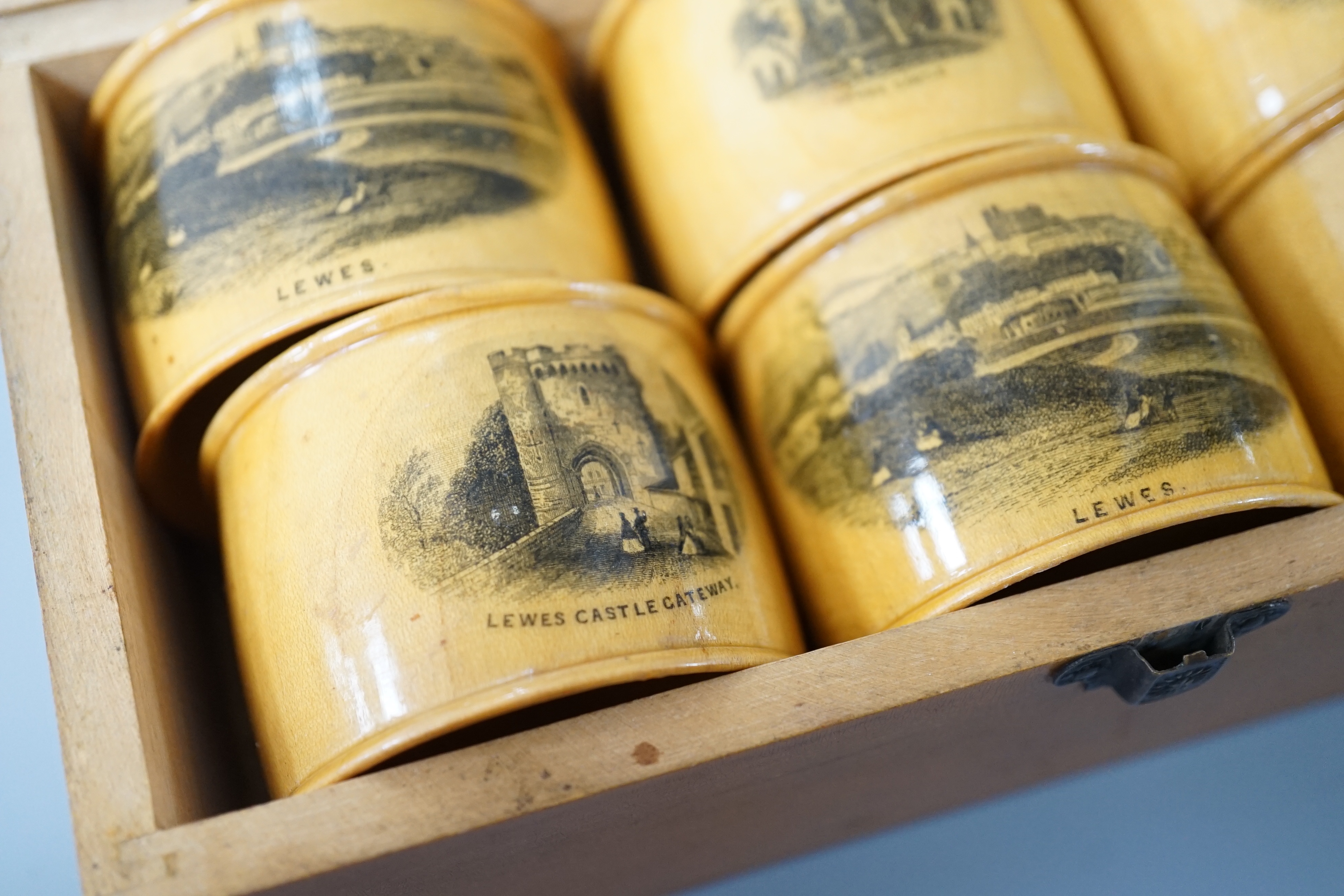 A set of 6 late 19th century mauchline ware napkin rings decorated with scenes of Lewes, housed in matching box. 18cm